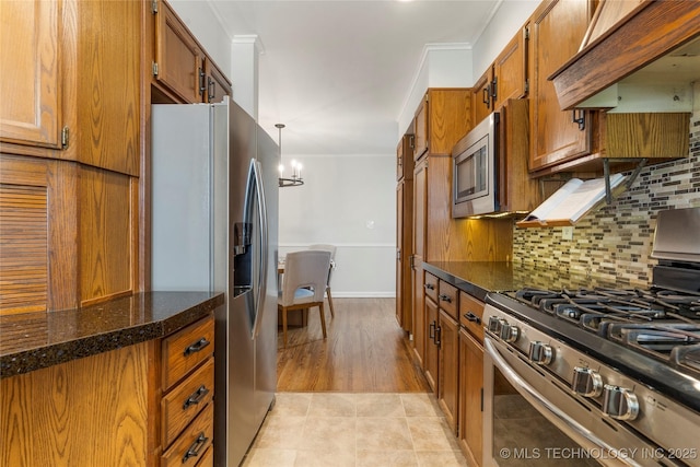5914 E 26th St, Tulsa, OK 74114 - kitchen with stainless steel appliances, premium range hood, brown cabinetry, ornamental molding, and a chandelier