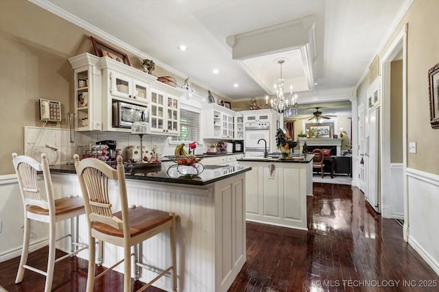 1110 N Renaissance Dr, Sand Springs, OK 74063 - kitchen with stainless steel microwave, dark countertops, a peninsula, a ceiling fan, and oven
