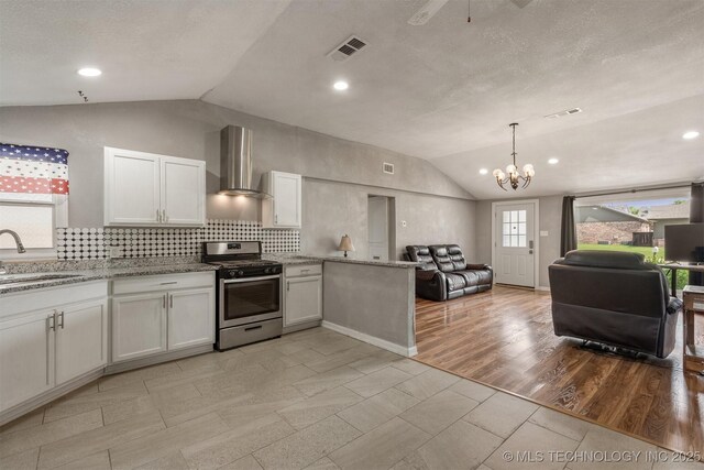 705 W Center St, Collinsville, OK 74021 - kitchen with stainless steel gas stove, wall chimney exhaust hood, lofted ceiling, open floor plan, and white cabinets