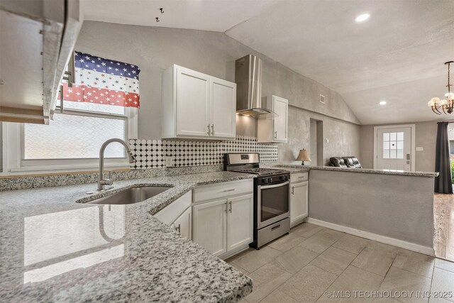 705 W Center St, Collinsville, OK 74021 - kitchen with stainless steel range with gas stovetop, wall chimney range hood, lofted ceiling, a peninsula, and white cabinets