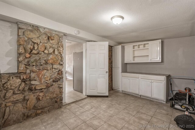 705 W Center St, Collinsville, OK 74021 - unfurnished dining area featuring a textured ceiling and light tile patterned floors