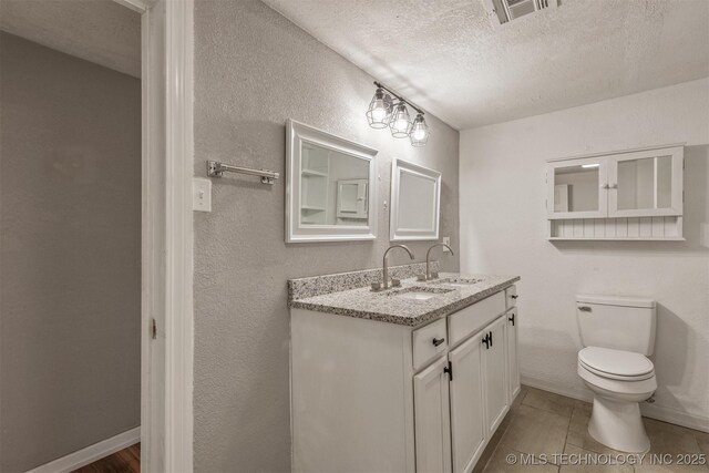 705 W Center St, Collinsville, OK 74021 - bathroom featuring a textured ceiling, vanity, and a textured wall