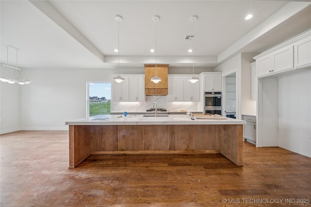 2614 E 134th Cir S, Bixby, OK 74008 - kitchen with a large island, light countertops, wood finished floors, white cabinetry, and stainless steel double oven