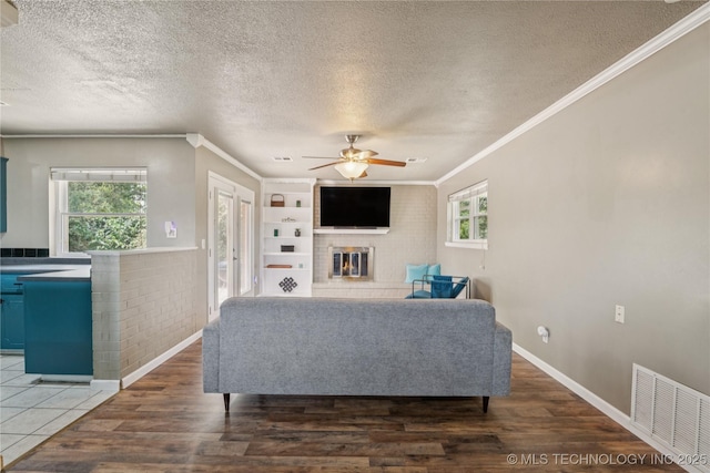 810 N 3rd St, Jenks, OK 74037 - living area featuring a brick fireplace, ornamental molding, a ceiling fan, a textured ceiling, and wood finished floors
