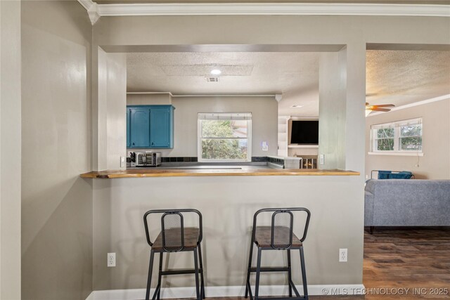 810 N 3rd St, Jenks, OK 74037 - kitchen with blue cabinets, a textured ceiling, a breakfast bar, ornamental molding, and open floor plan