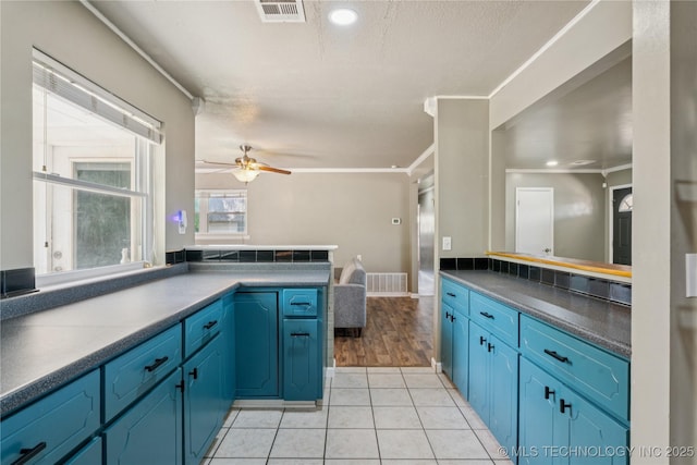 810 N 3rd St, Jenks, OK 74037 - kitchen featuring ceiling fan, light tile patterned floors, a peninsula, blue cabinetry, and ornamental molding