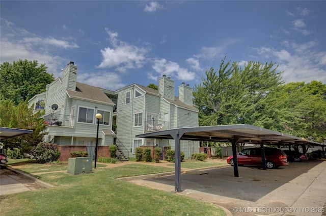 1730 E 67th St Unit K102, Tulsa, OK 74136 - rear view of property featuring a chimney, covered parking, and a yard