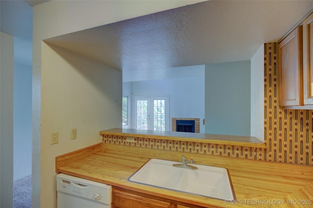 1730 E 67th St Unit K102, Tulsa, OK 74136 - kitchen featuring dishwasher, a textured ceiling, and a fireplace