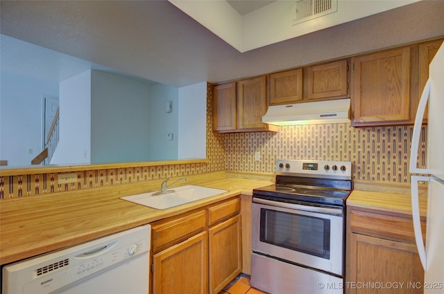 1730 E 67th St Unit K102, Tulsa, OK 74136 - kitchen with white appliances, under cabinet range hood, backsplash, wood counters, and brown cabinets
