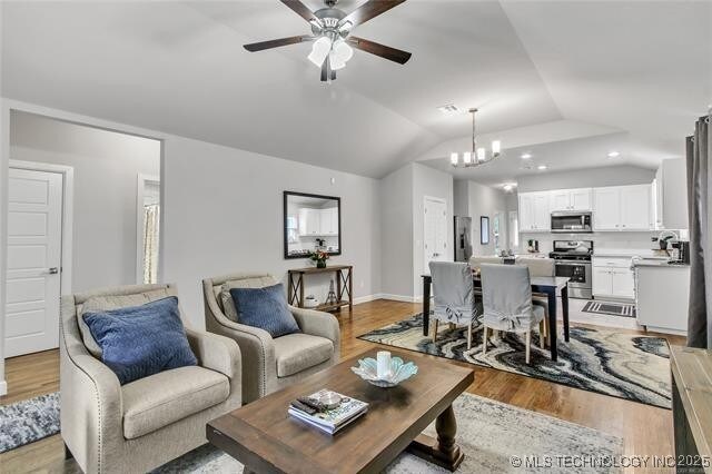 1332 N Denver Ave, Tulsa, OK 74106 - living room featuring light wood-style floors, vaulted ceiling, ceiling fan, and a chandelier