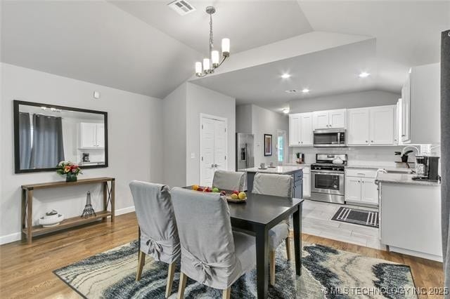 1332 N Denver Ave, Tulsa, OK 74106 - dining room featuring vaulted ceiling, light wood finished floors, and a chandelier