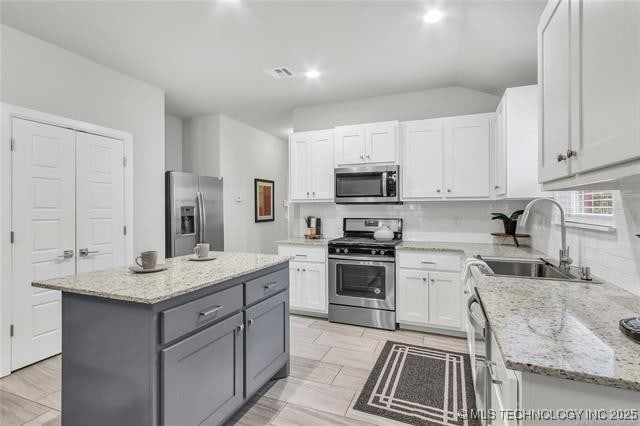 1332 N Denver Ave, Tulsa, OK 74106 - kitchen with stainless steel appliances, gray cabinets, white cabinets, a kitchen island, and decorative backsplash