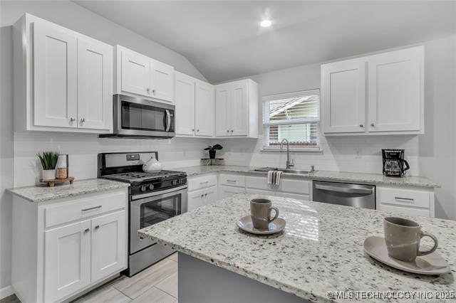 1332 N Denver Ave, Tulsa, OK 74106 - kitchen featuring appliances with stainless steel finishes, lofted ceiling, white cabinetry, and light stone countertops