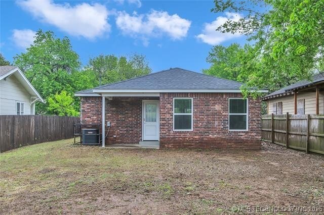 1332 N Denver Ave, Tulsa, OK 74106 - back of property with brick siding, a fenced backyard, and a shingled roof