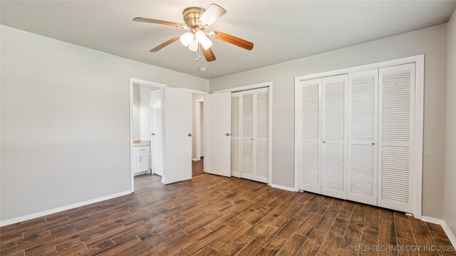 2974 E 77th Pl, Tulsa, OK 74136 - unfurnished bedroom featuring dark wood finished floors, multiple closets, ceiling fan, and connected bathroom