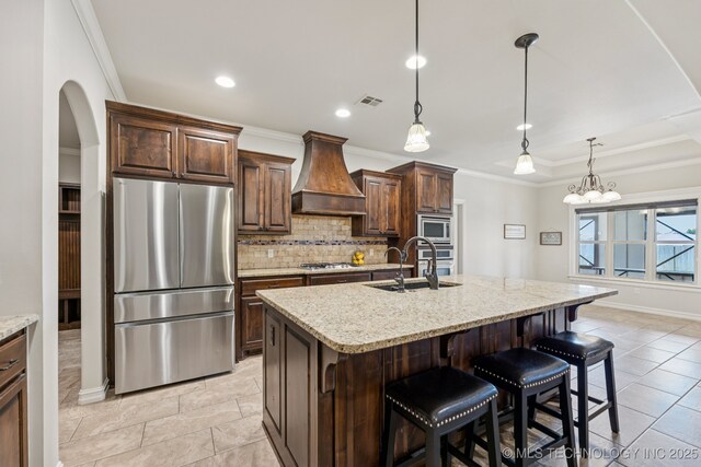 1956 E 172nd St S, Mounds, OK 74047 - kitchen featuring appliances with stainless steel finishes, custom range hood, tasteful backsplash, arched walkways, and a kitchen breakfast bar