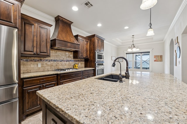 1956 E 172nd St S, Mounds, OK 74047 - kitchen featuring appliances with stainless steel finishes, custom exhaust hood, light stone counters, backsplash, and recessed lighting