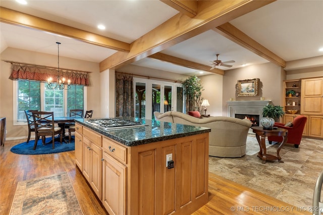 9034 S Maplewood Ave, Tulsa, OK 74137 - kitchen featuring stainless steel gas stovetop, a warm lit fireplace, a chandelier, beamed ceiling, and a ceiling fan