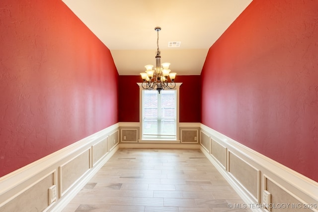 18312 E 46th St, Tulsa, OK 74134 - unfurnished room featuring a chandelier, light wood-style floors, a wainscoted wall, vaulted ceiling, and a decorative wall