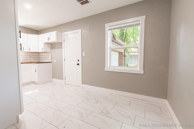 812 N Delaware Pl, Tulsa, OK 74110 - kitchen with white cabinetry, light marble finish flooring, tasteful backsplash, and dark countertops