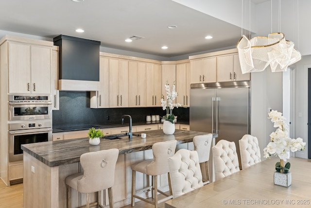 12622 S Granite Ave E, Bixby, OK 74008 - kitchen with appliances with stainless steel finishes, a kitchen bar, backsplash, recessed lighting, and a kitchen island with sink