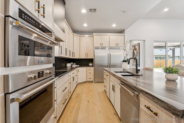 12622 S Granite Ave E, Bixby, OK 74008 - kitchen featuring appliances with stainless steel finishes, tasteful backsplash, light wood-style flooring, recessed lighting, and dark stone countertops
