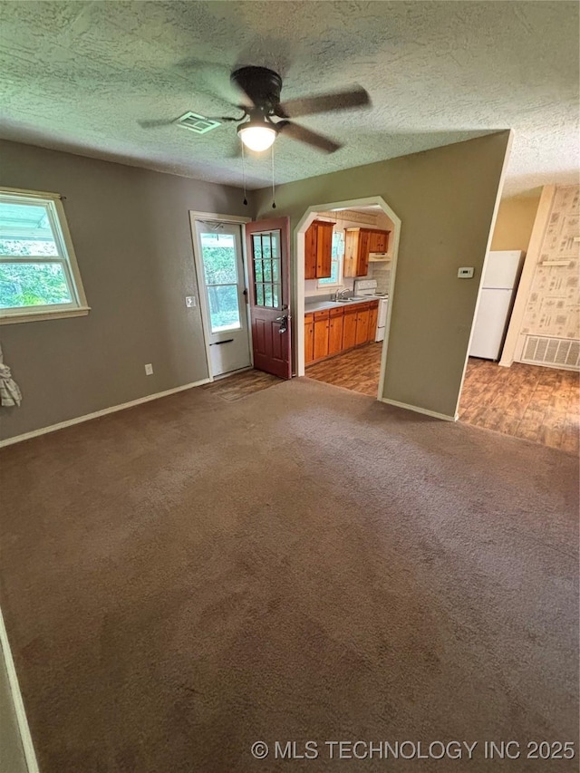 14274 W Clyde Maher, Tahlequah, OK 74464 - unfurnished living room with a ceiling fan, dark carpet, a textured ceiling, and arched walkways