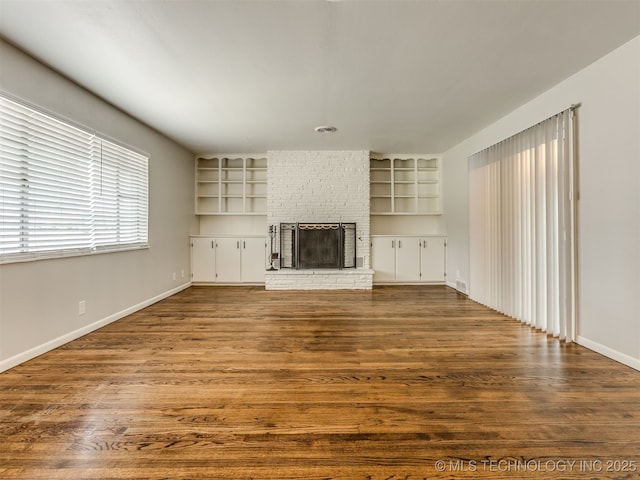 4512 SE Frank Phillips Blvd, Bartlesville, OK 74006 - unfurnished living room with a brick fireplace, dark wood-style floors, and built in shelves