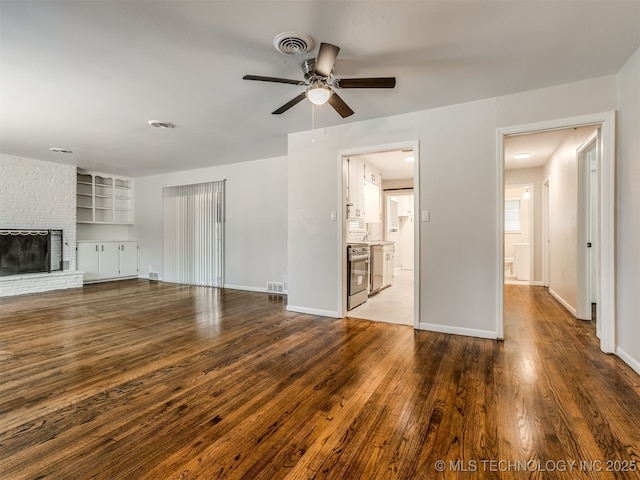 4512 SE Frank Phillips Blvd, Bartlesville, OK 74006 - unfurnished living room with ceiling fan, wood finished floors, and a brick fireplace