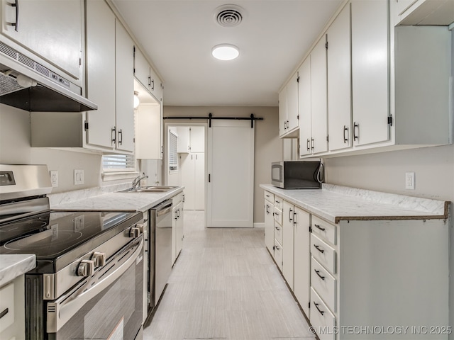 4512 SE Frank Phillips Blvd, Bartlesville, OK 74006 - kitchen with appliances with stainless steel finishes, exhaust hood, a barn door, light countertops, and white cabinetry