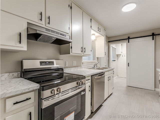 4512 SE Frank Phillips Blvd, Bartlesville, OK 74006 - kitchen with stainless steel appliances, under cabinet range hood, a barn door, and white cabinets