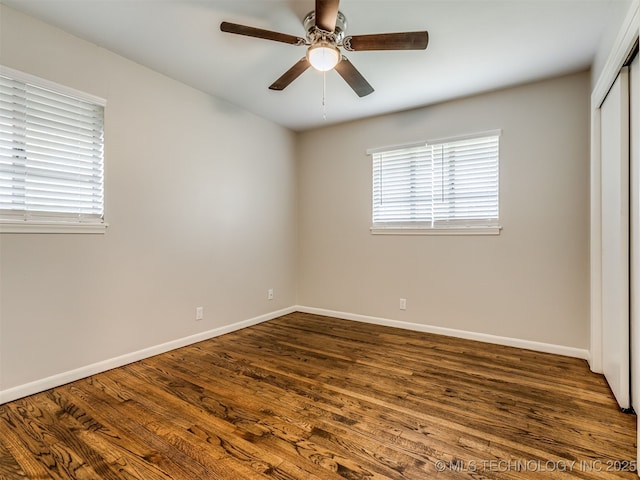 4512 SE Frank Phillips Blvd, Bartlesville, OK 74006 - unfurnished bedroom with multiple windows, a closet, dark wood-type flooring, and a ceiling fan