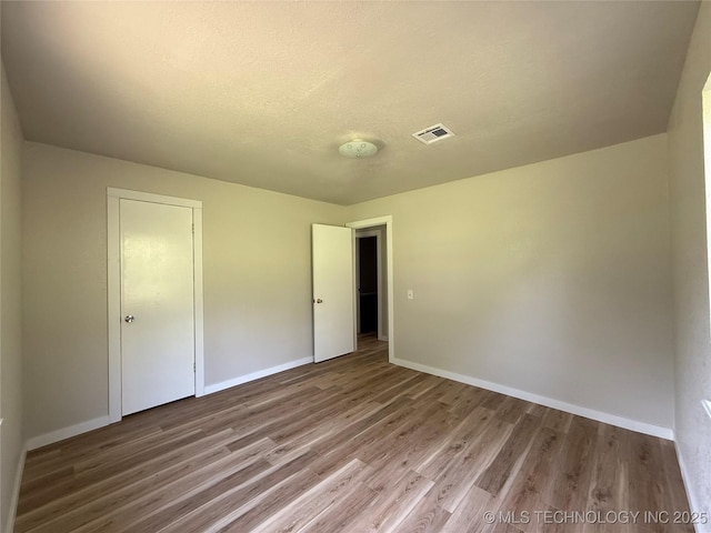 97951 S 4489th Rd, Vian, OK 74962 - unfurnished bedroom with wood finished floors, a textured ceiling, and a closet
