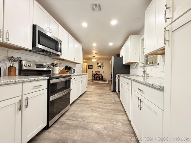 1604 N 2nd Ave, Warner, OK 74469 - kitchen with stainless steel appliances, white cabinets, tasteful backsplash, recessed lighting, and light stone counters