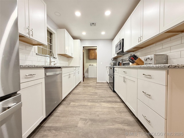 1604 N 2nd Ave, Warner, OK 74469 - kitchen featuring stainless steel appliances, light wood-type flooring, washer / dryer, recessed lighting, and tasteful backsplash