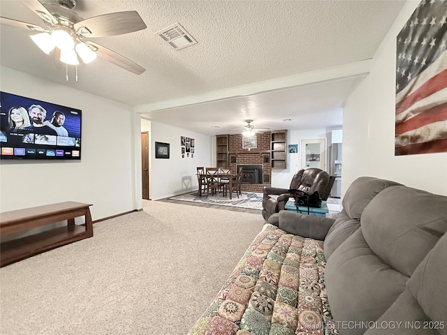 1604 N 2nd Ave, Warner, OK 74469 - living room with ceiling fan, a textured ceiling, carpet flooring, a brick fireplace, and built in shelves