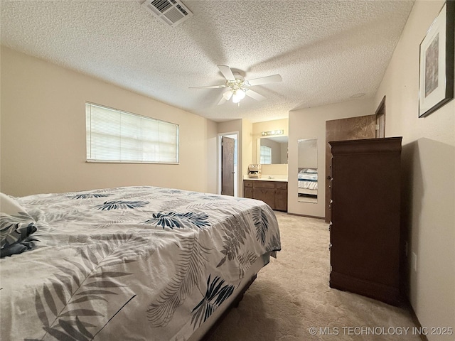 1604 N 2nd Ave, Warner, OK 74469 - bedroom featuring light carpet, ensuite bathroom, a textured ceiling, and ceiling fan