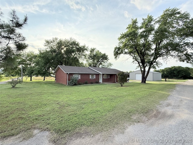 1604 N 2nd Ave, Warner, OK 74469 - ranch-style house with a front yard, driveway, a detached garage, brick siding, and an outbuilding