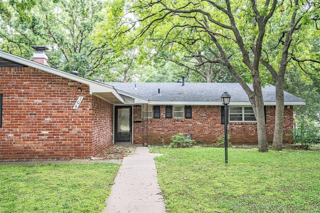 104 Laurel Pl, Bartlesville, OK 74003 - view of front of home featuring a front lawn, brick siding, a chimney, and roof with shingles