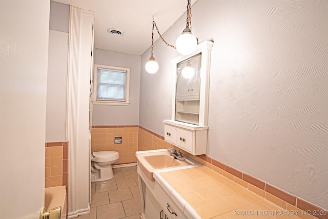 104 Laurel Pl, Bartlesville, OK 74003 - full bath featuring tile patterned floors, vanity, a tub, a wainscoted wall, and tile walls