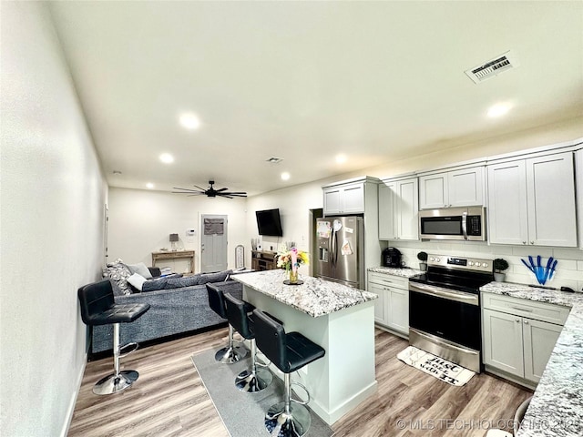 2125 N Lansing Ave W, Tulsa, OK 74106 - kitchen with appliances with stainless steel finishes, open floor plan, light wood-style flooring, ceiling fan, and tasteful backsplash