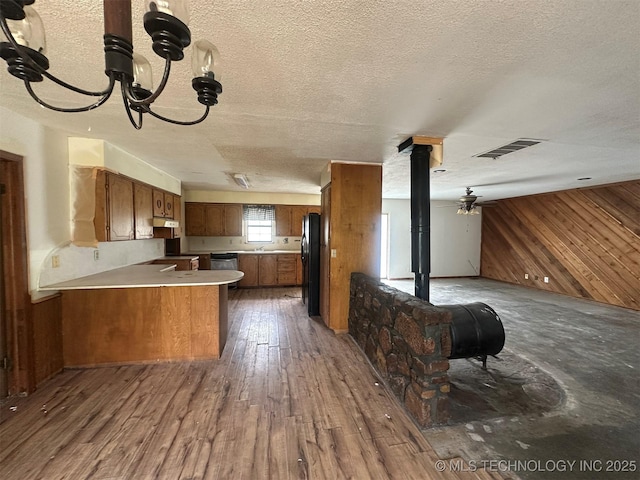 51698 W 139th St S, Drumright, OK 74030 - kitchen featuring open floor plan, wooden walls, a peninsula, brown cabinetry, and light countertops