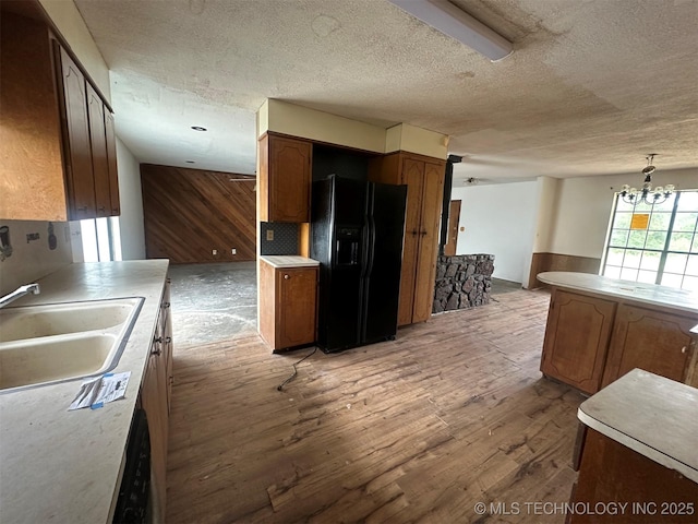51698 W 139th St S, Drumright, OK 74030 - kitchen featuring black appliances, light wood-style floors, a textured ceiling, wood walls, and a chandelier