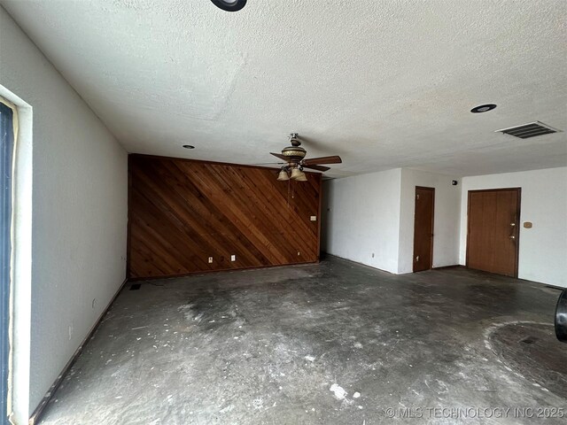 51698 W 139th St S, Drumright, OK 74030 - unfurnished living room with wooden walls, ceiling fan, concrete floors, and a textured ceiling