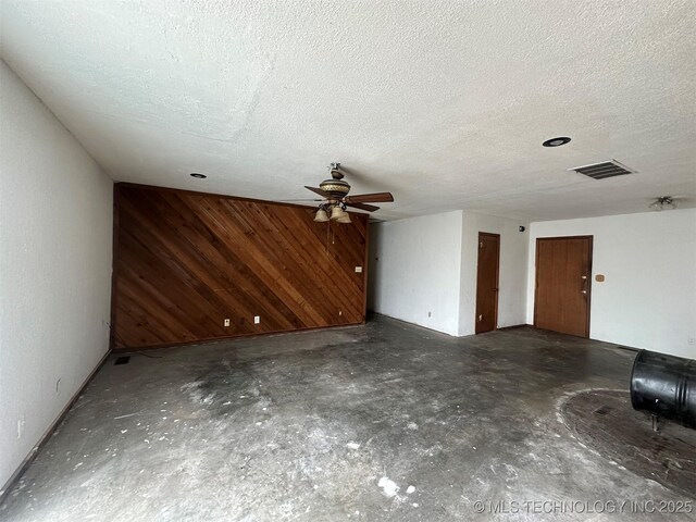 51698 W 139th St S, Drumright, OK 74030 - unfurnished living room featuring concrete floors, wood walls, ceiling fan, and a textured ceiling
