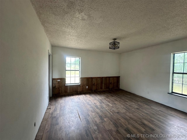 51698 W 139th St S, Drumright, OK 74030 - spare room featuring dark wood-style flooring, wainscoting, a textured ceiling, and wood walls