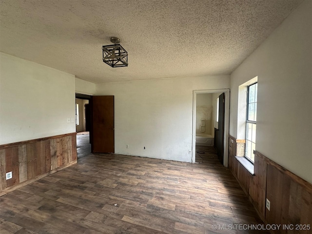 51698 W 139th St S, Drumright, OK 74030 - unfurnished room featuring dark wood finished floors, a textured ceiling, a wainscoted wall, and wood walls
