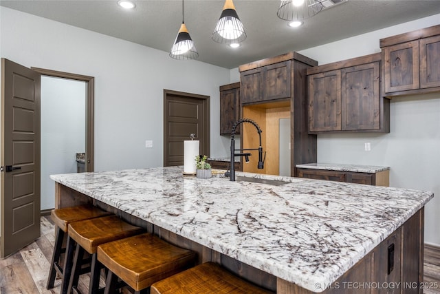 101 Dunn, Caddo, OK 74729 - kitchen with light wood-style flooring, light stone counters, dark brown cabinetry, and recessed lighting