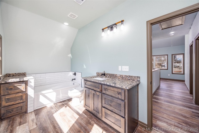 101 Dunn, Caddo, OK 74729 - full bathroom featuring a garden tub, wood finished floors, vanity, and lofted ceiling