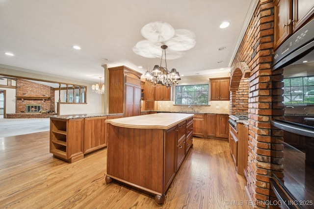 11637 W 86th St S, Sapulpa, OK 74066 - kitchen with a chandelier, a center island, light wood finished floors, ornamental molding, and decorative backsplash